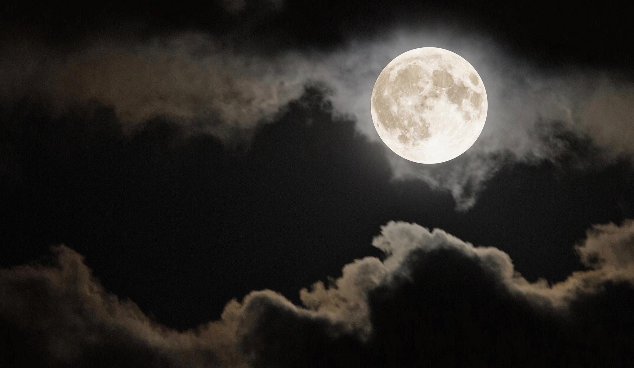 A bright full moon shining through dark clouds